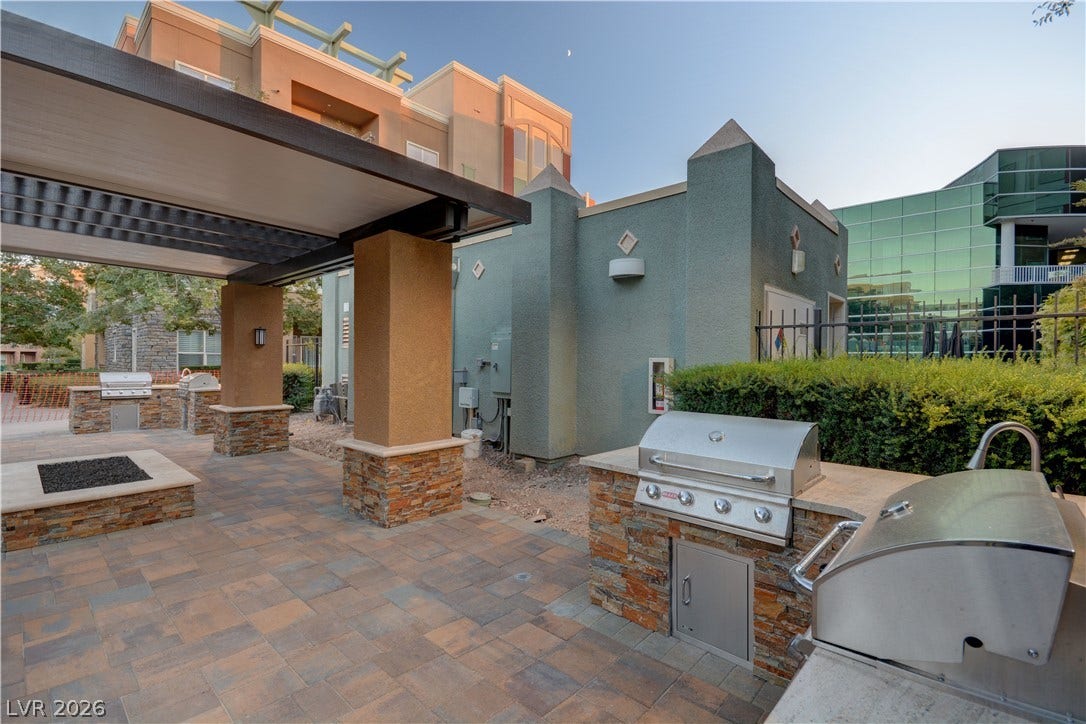 32 E Serene Avenue, #407, Las Vegas, NV 89123 An inviting outdoor kitchen area features stone-accented grilling stations and modern paving under a protective pavilion.