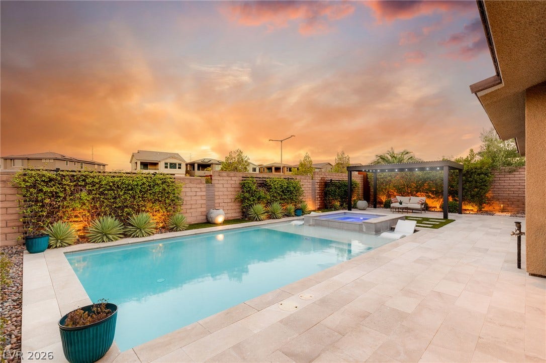 An inviting backyard oasis offers a sparkling pool and spa, perfect for relaxation and entertaining under the colorful sky.
