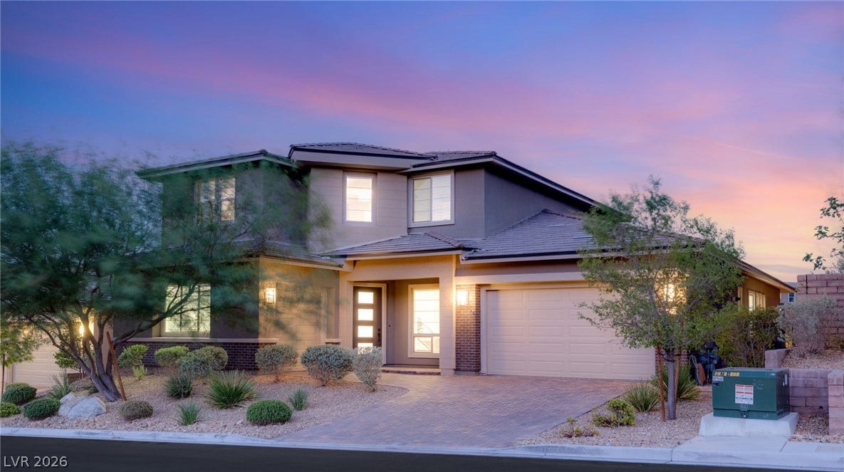 A striking modern home with paver driveway and well-manicured desert landscaping.