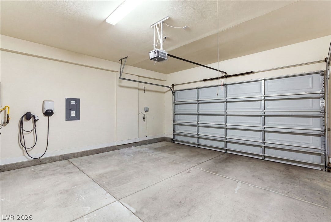 A well-lit garage features a smart electric vehicle charging station and a convenient garage door opener.