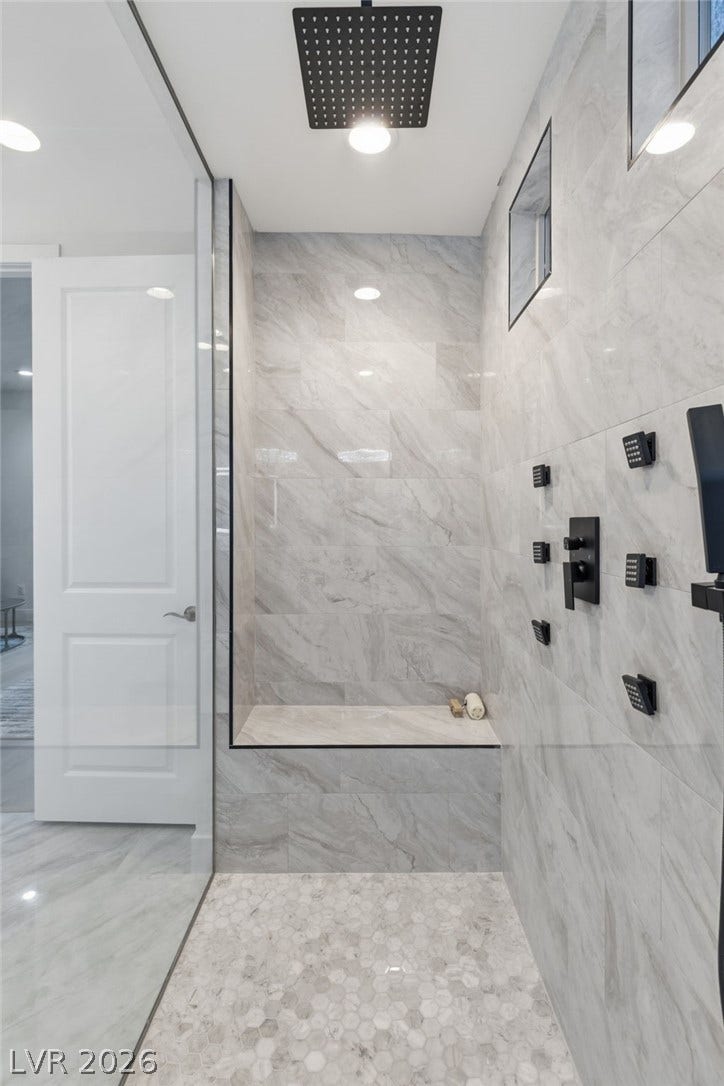Luxurious walk-in shower features full body spray jets and an integrated bench.