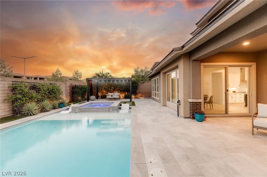 An inviting backyard oasis features a shimmering pool, relaxing spa, and covered patio for evening enjoyment.