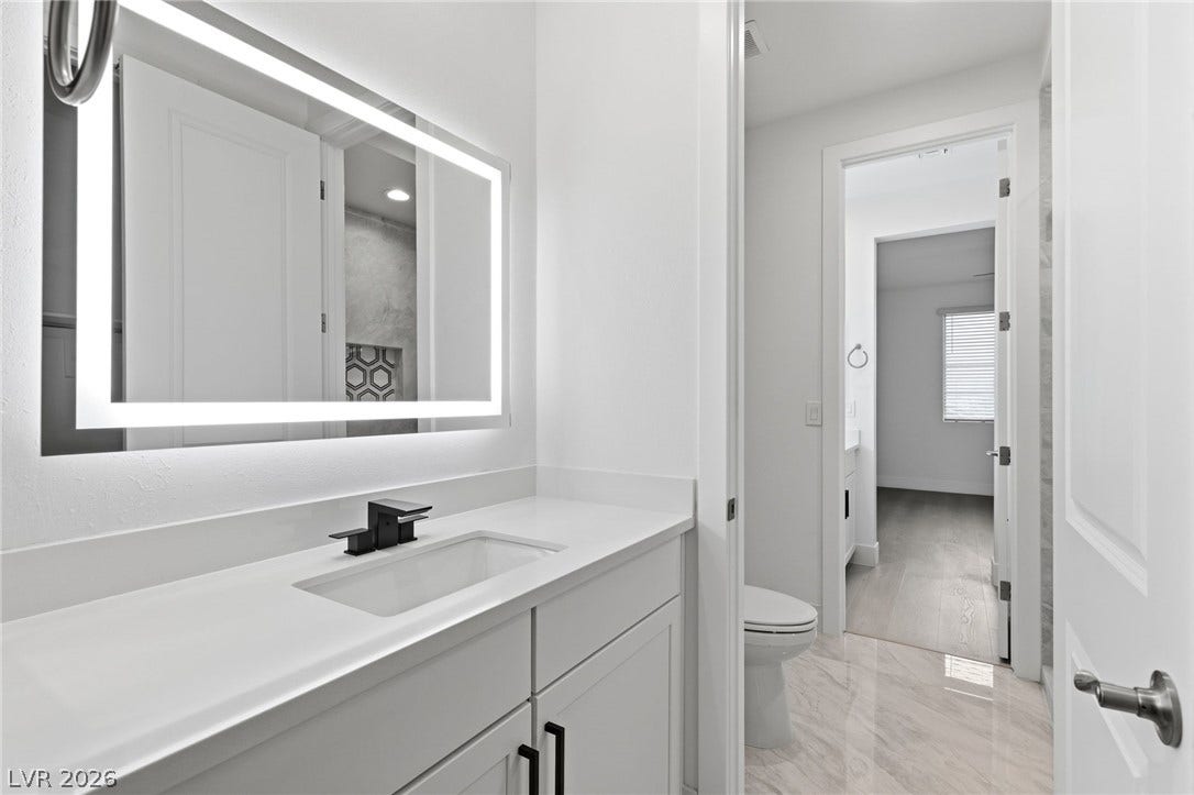 A well-lit vanity with a modern sink and a sleek mirror creates a refreshing ambiance in this bathroom.