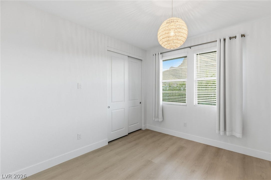 A well-lit bedroom features durable laminate flooring and mountain views from two generous windows.
