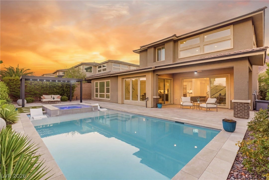 An inviting backyard oasis features a shimmering pool and hot tub under a charming pergola, perfect for twilight entertaining.
