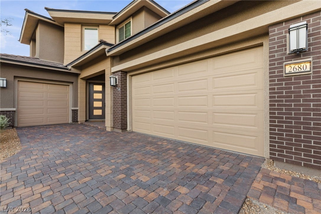 A striking exterior featuring a two-car garage and a meticulously paved driveway.