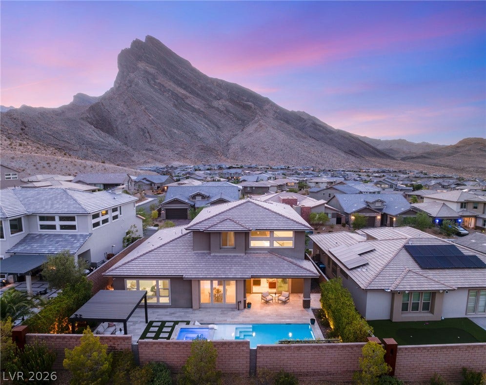 An aerial perspective reveals a private pool oasis against a dramatic mountain backdrop, surrounded by a serene neighborhood.