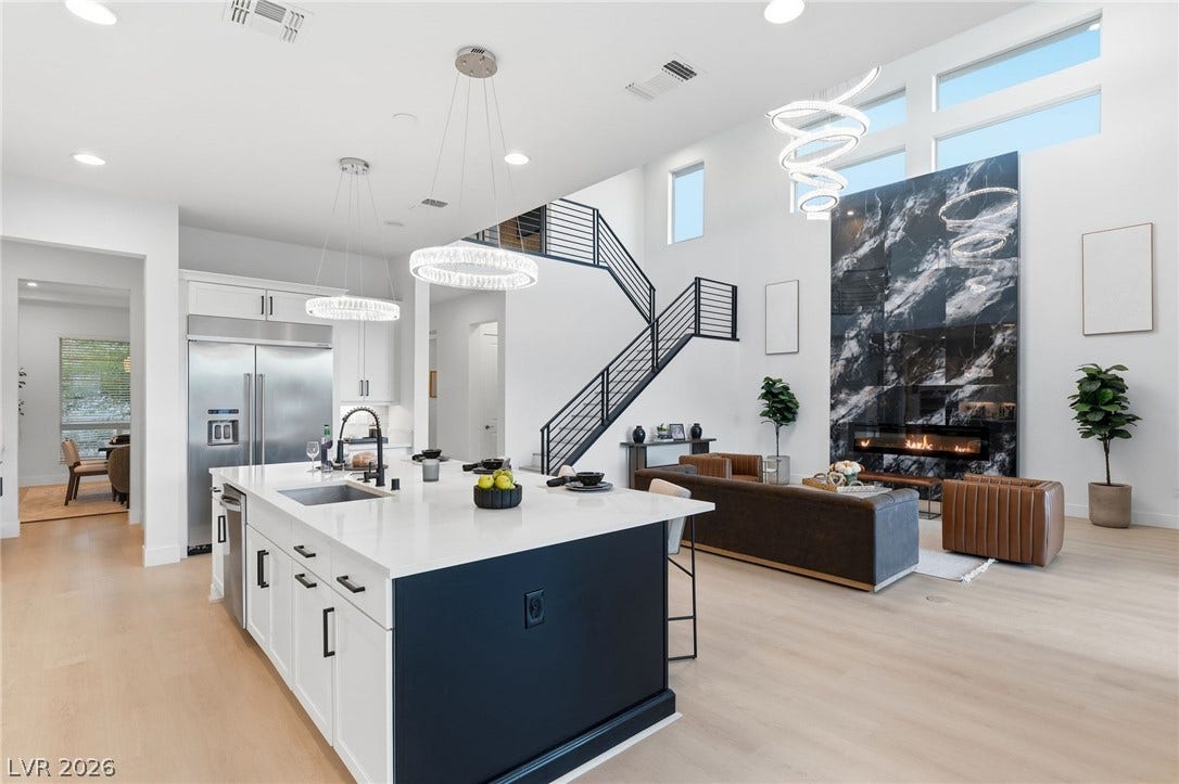 An open concept living area showcases soaring ceilings, a modern fireplace, and a sleek kitchen island.