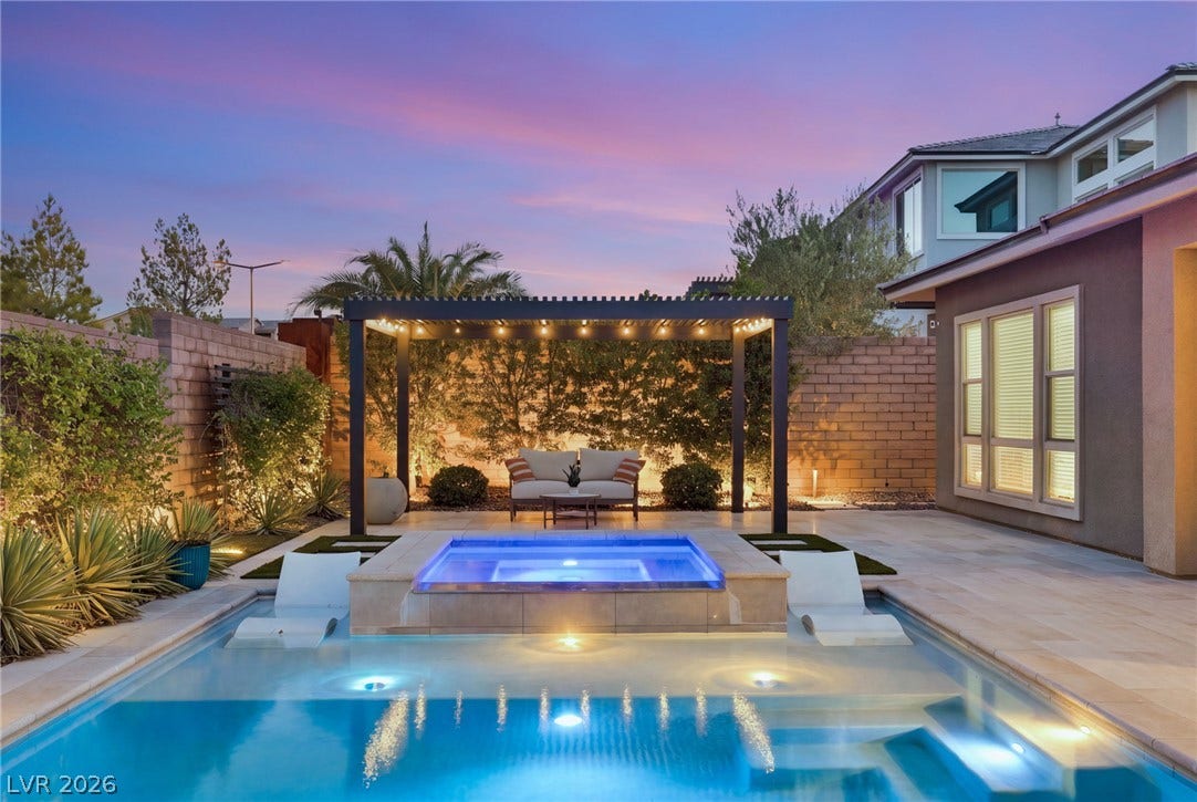 An inviting backyard oasis offers a sparkling pool, integrated spa, and a shaded pergola for elegant outdoor relaxation.