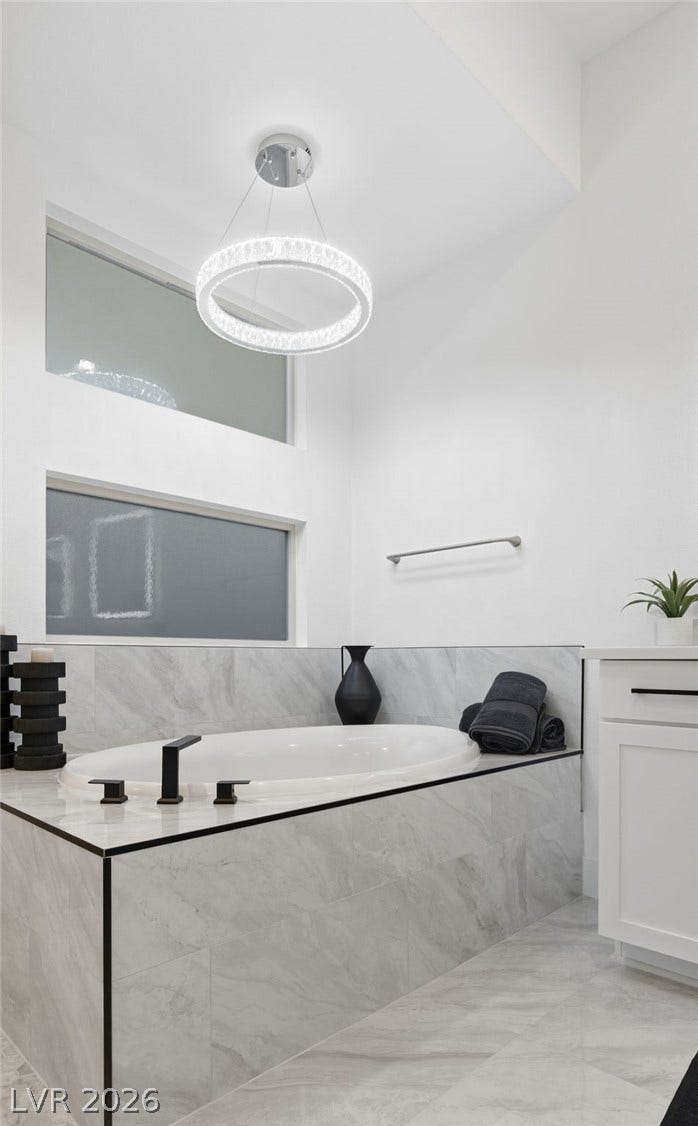 Indulge in a relaxing soak within this primary bathroom, featuring a built-in tub and elegant tiled finishes.