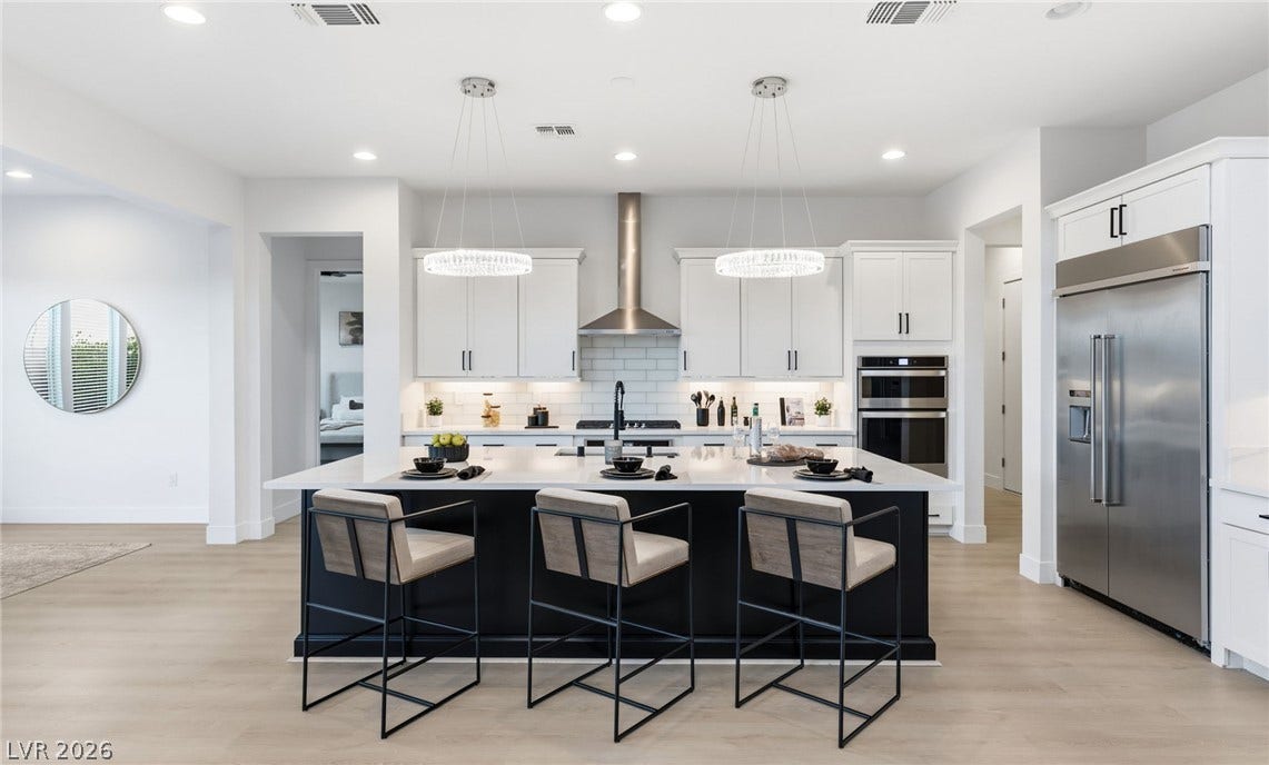 A well-appointed kitchen features a large island with seating, stainless steel appliances, and elegant pendant lighting.