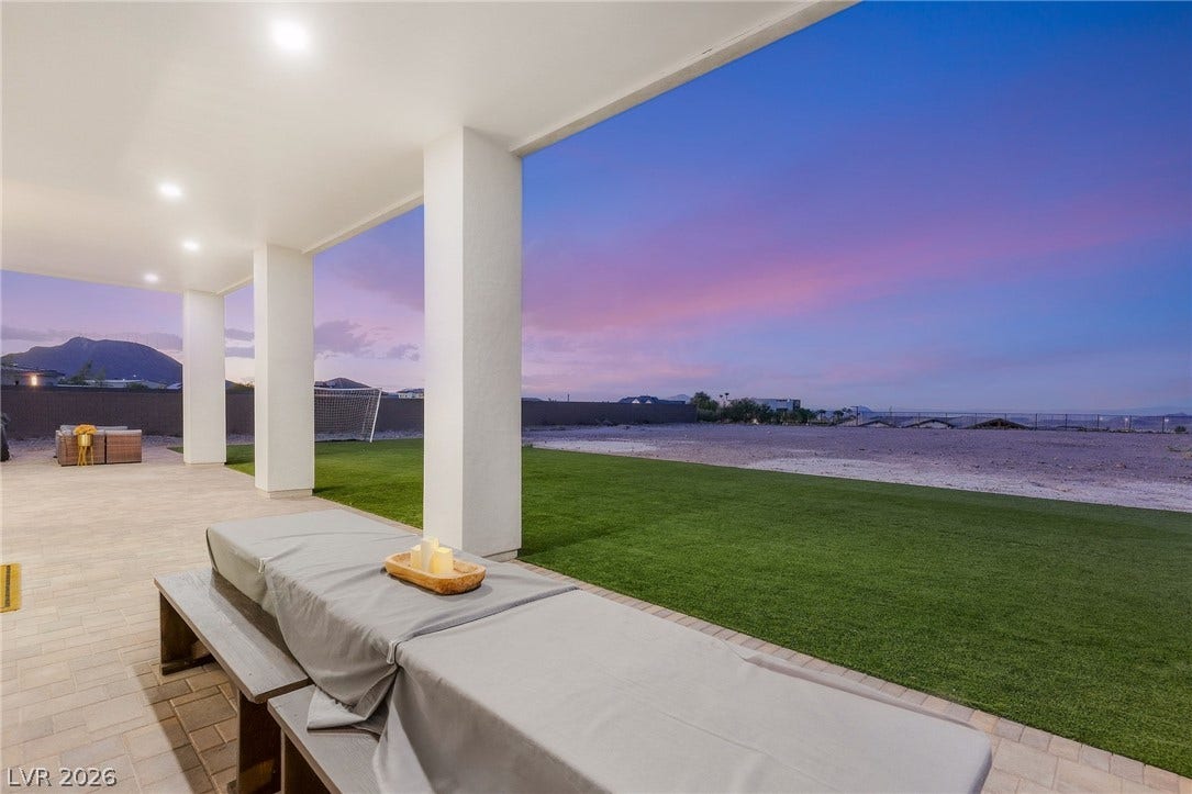 324 Wanda Road, Henderson, NV 89002 A spacious covered patio overlooks the manicured green lawn under a vibrant twilight sky.