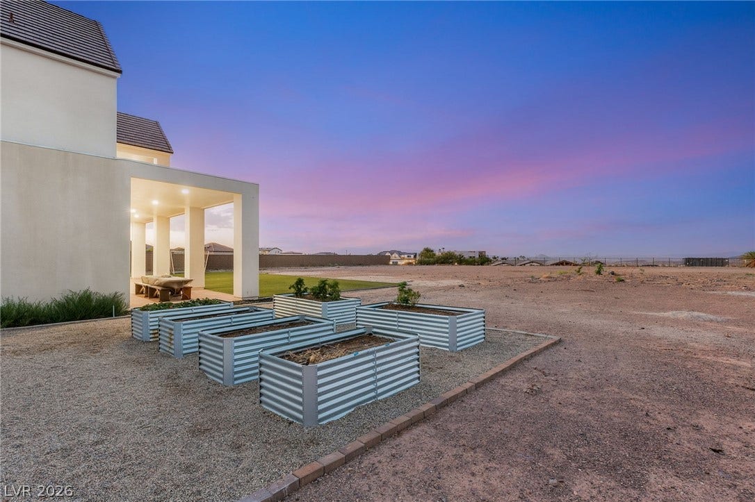 324 Wanda Road, Henderson, NV 89002 A spacious backyard area includes raised garden beds set against a backdrop of twilight skies.
