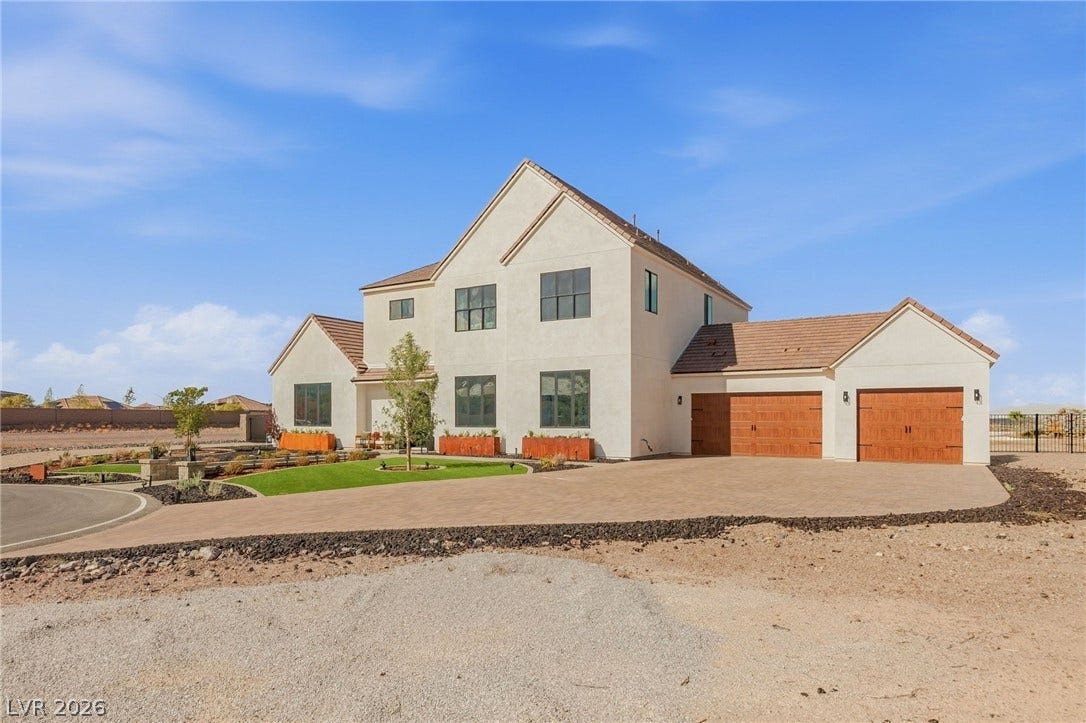 324 Wanda Road, Henderson, NV 89002 An expansive paved driveway leads to a classic stucco exterior with warm wood garage doors.