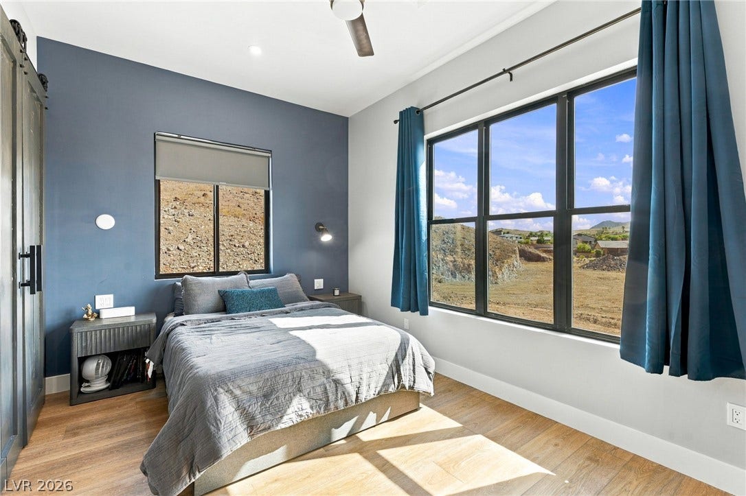 324 Wanda Road, Henderson, NV 89002 Large windows framing hillside views anchor this contemporary bedroom with wood floors.