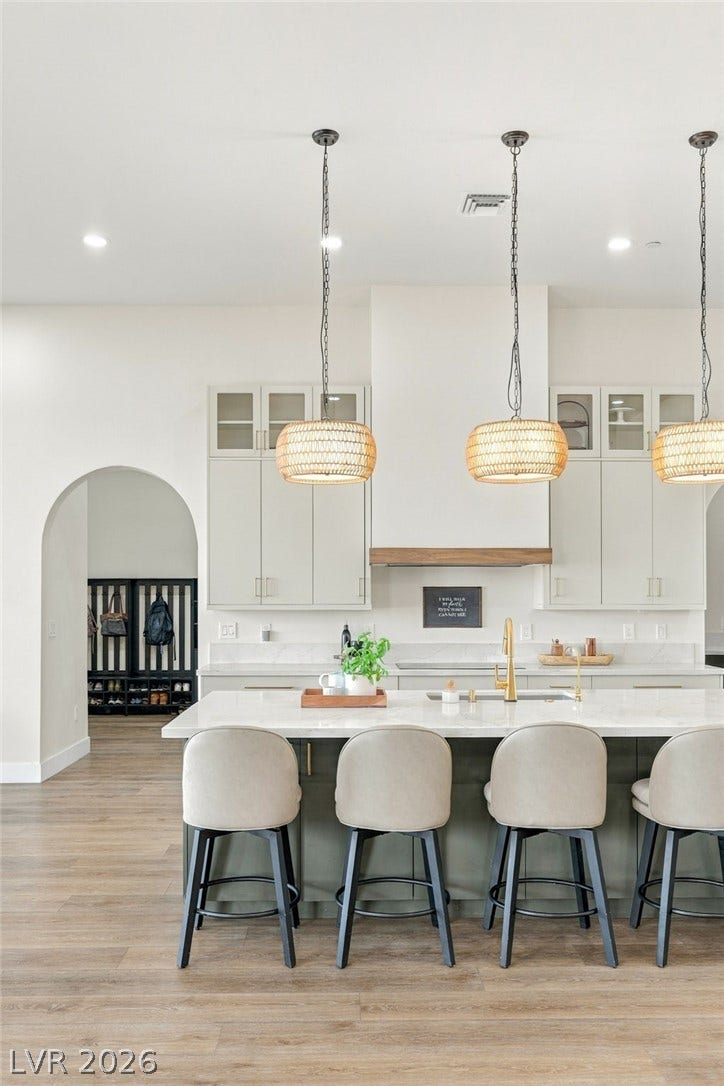 324 Wanda Road, Henderson, NV 89002 An elegant arched doorway opens into this modern kitchen featuring a stone-topped island and light wood flooring.