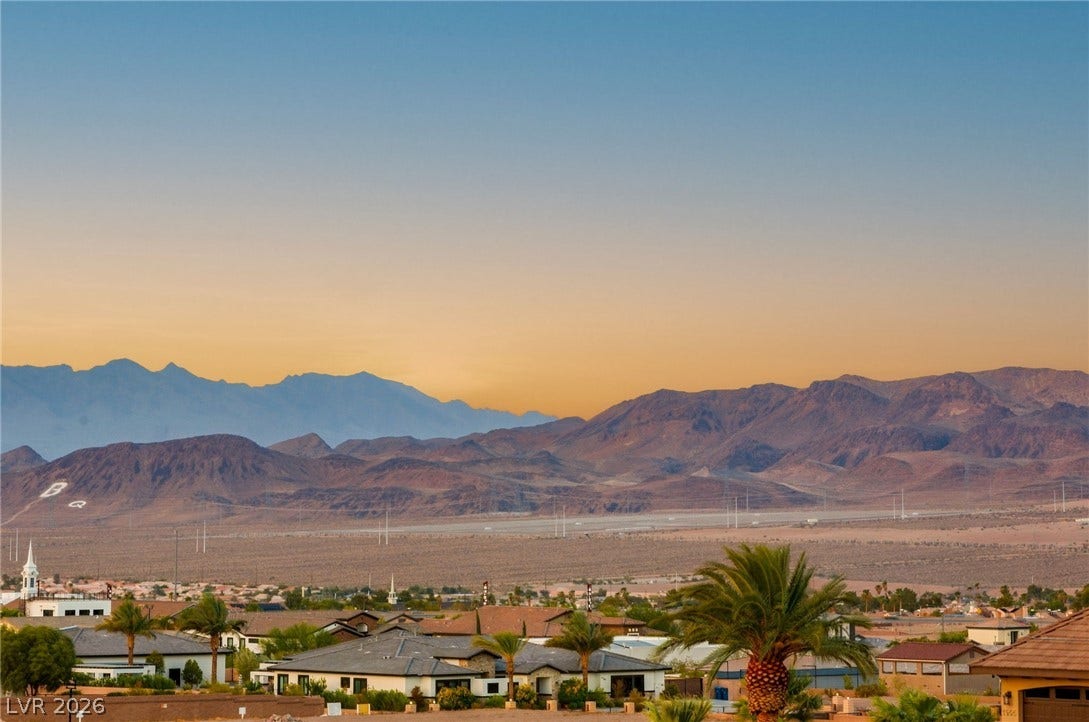 324 Wanda Road, Henderson, NV 89002 Dramatic mountain ranges rise behind a peaceful desert neighborhood during sunset.