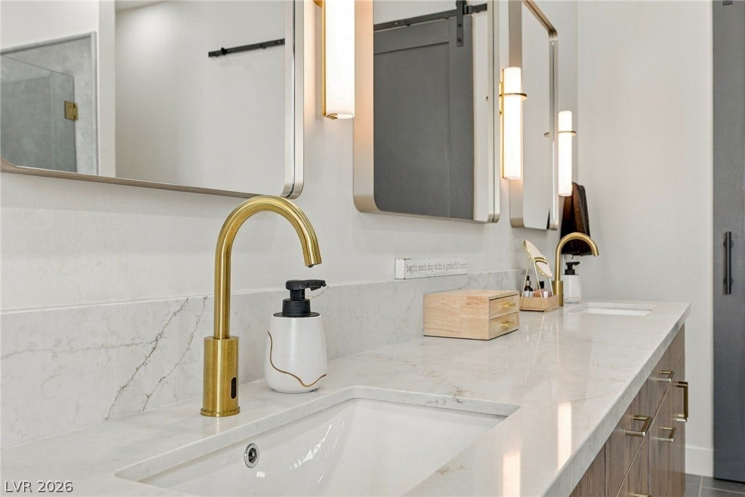 324 Wanda Road, Henderson, NV 89002 Elegant brass hardware accents a spacious stone vanity in this modern bathroom setup.