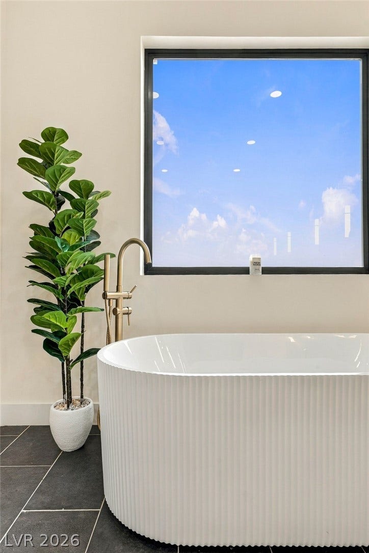 324 Wanda Road, Henderson, NV 89002 A modern soaking tub sits beneath a large window framing serene sky views.