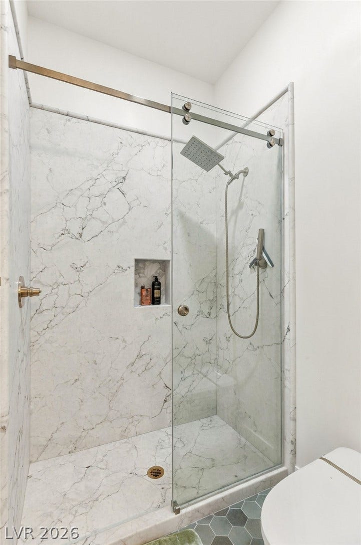 324 Wanda Road, Henderson, NV 89002 Floor-to-ceiling marble tile and sleek glass doors elevate this modern walk-in shower design.