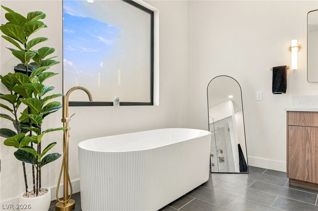 324 Wanda Road, Henderson, NV 89002 A modern soaking tub rests on dark tile flooring beneath a large picture window.