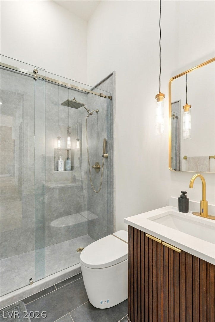 324 Wanda Road, Henderson, NV 89002 Elegant gold hardware pairs beautifully with a glass-enclosed shower and wood-paneled vanity.