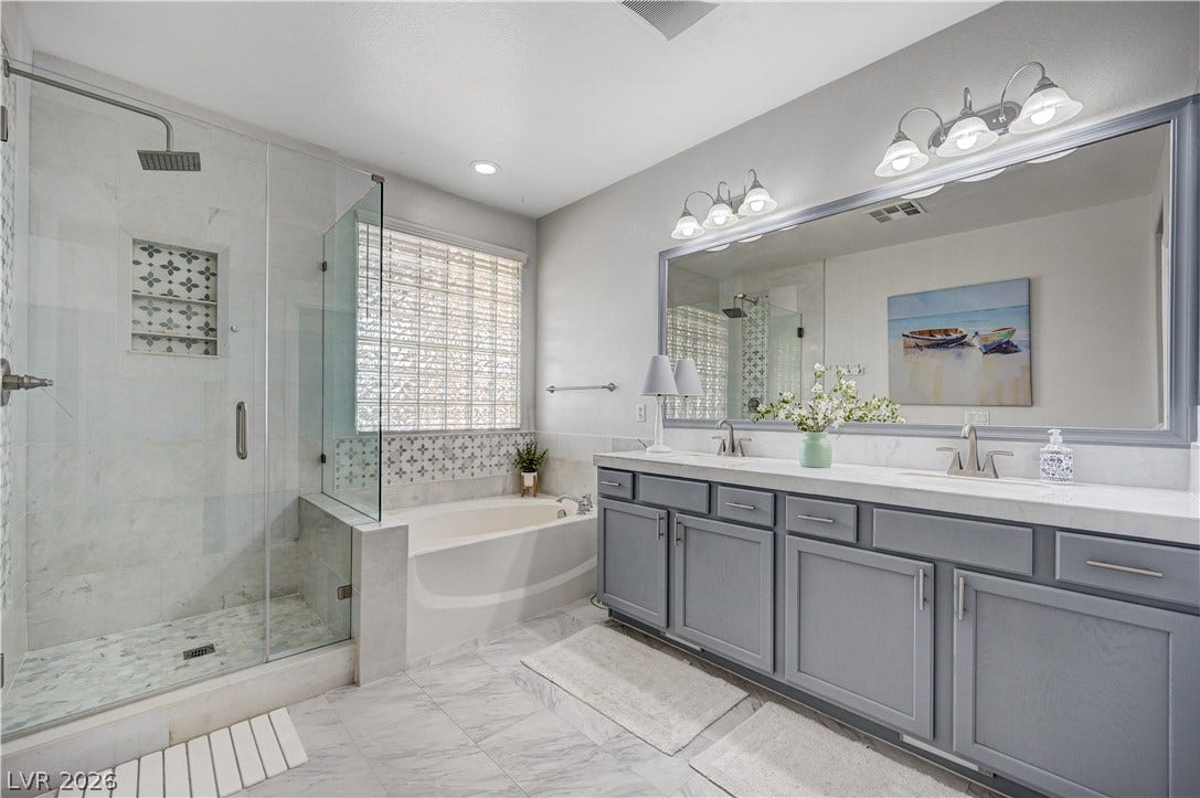 A glass-enclosed shower alongside a deep soaking tub creates a spa-like master bathroom atmosphere.
