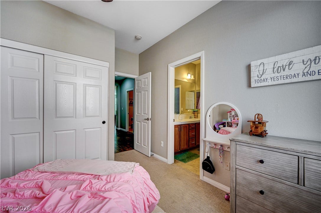 A spacious bedroom features direct access to an en suite bathroom and cozy carpeted flooring.