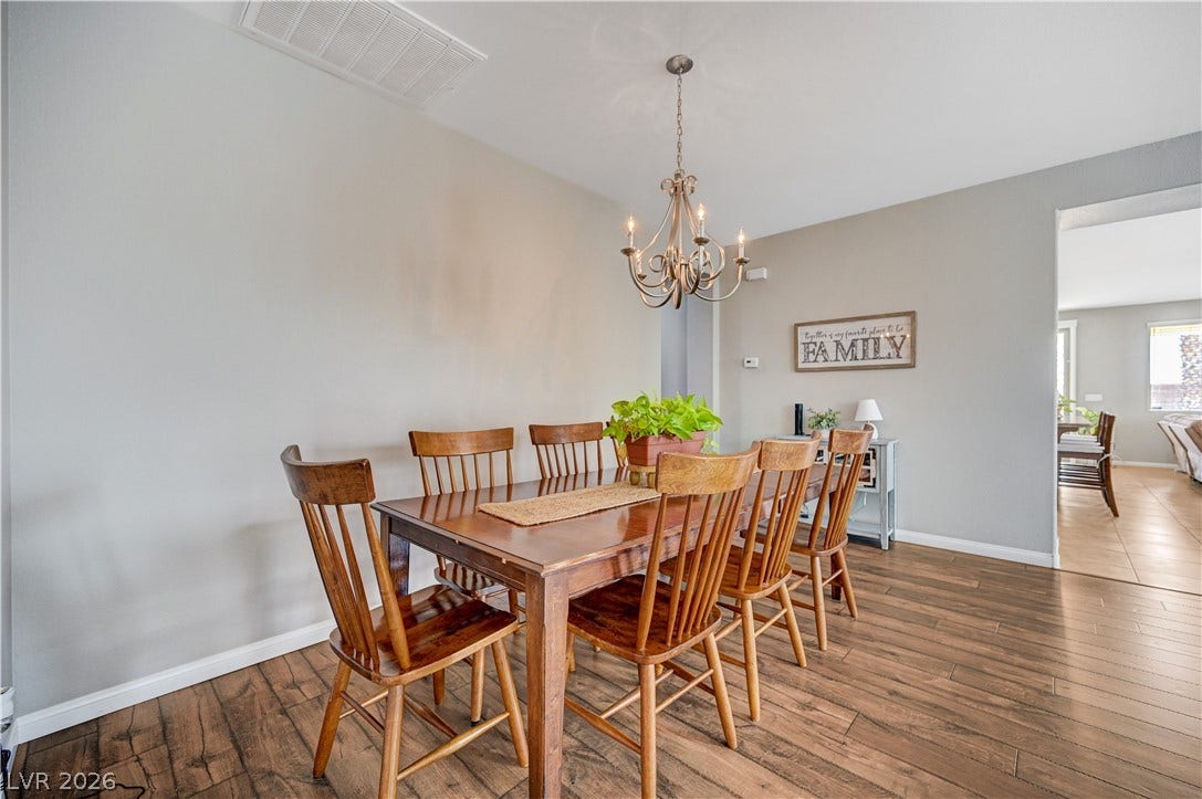 Rich wood-look flooring and an elegant chandelier anchor this classic dining space.