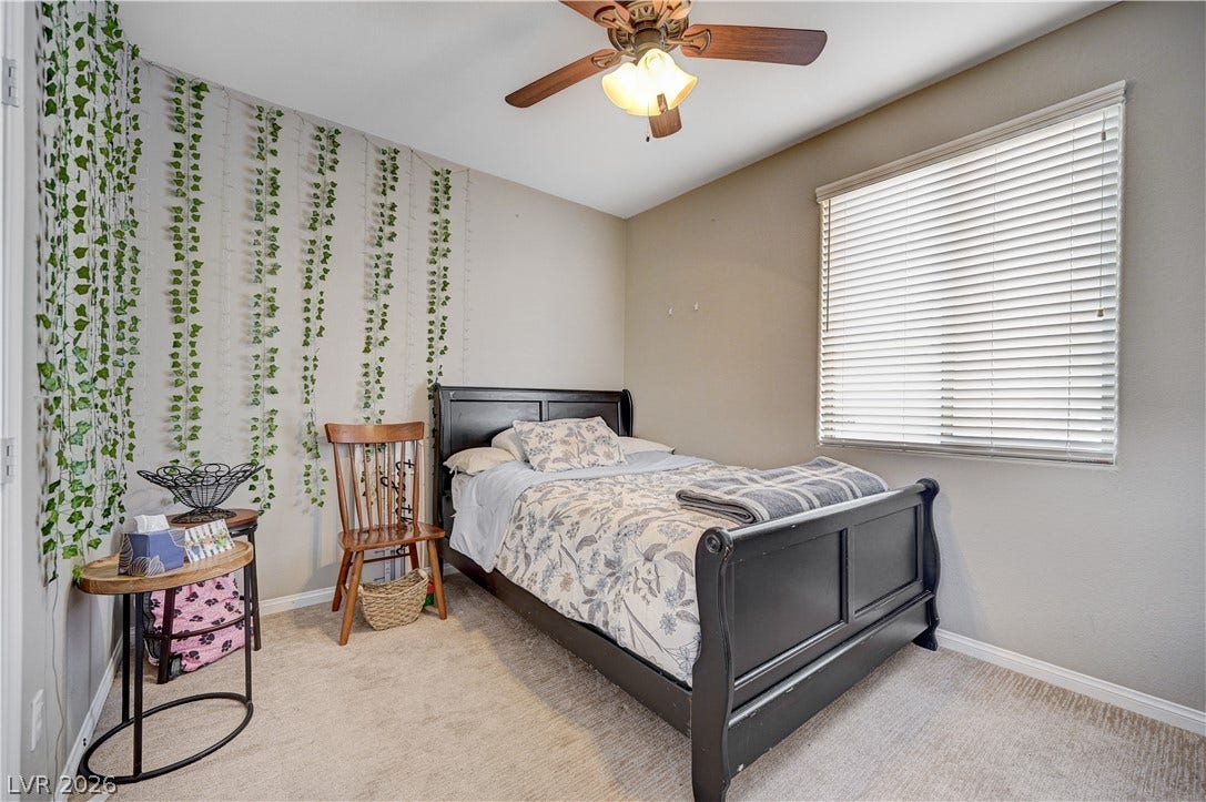 A spacious bedroom offers plush neutral carpeting and a wide window with integrated blinds.