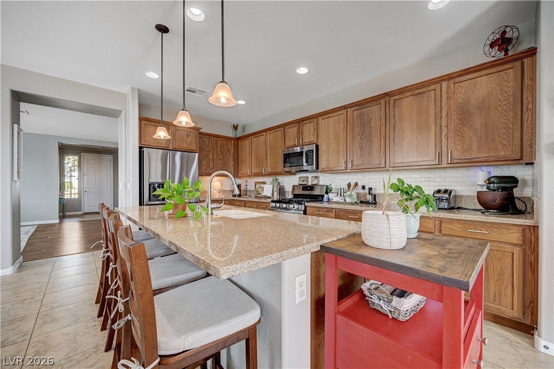 Warm wood cabinetry and granite countertops anchor this kitchen designed with a spacious central island.