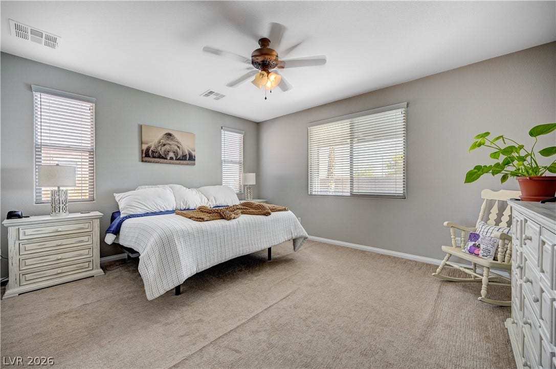 Generous window installations fill this carpeted bedroom space with natural light.
