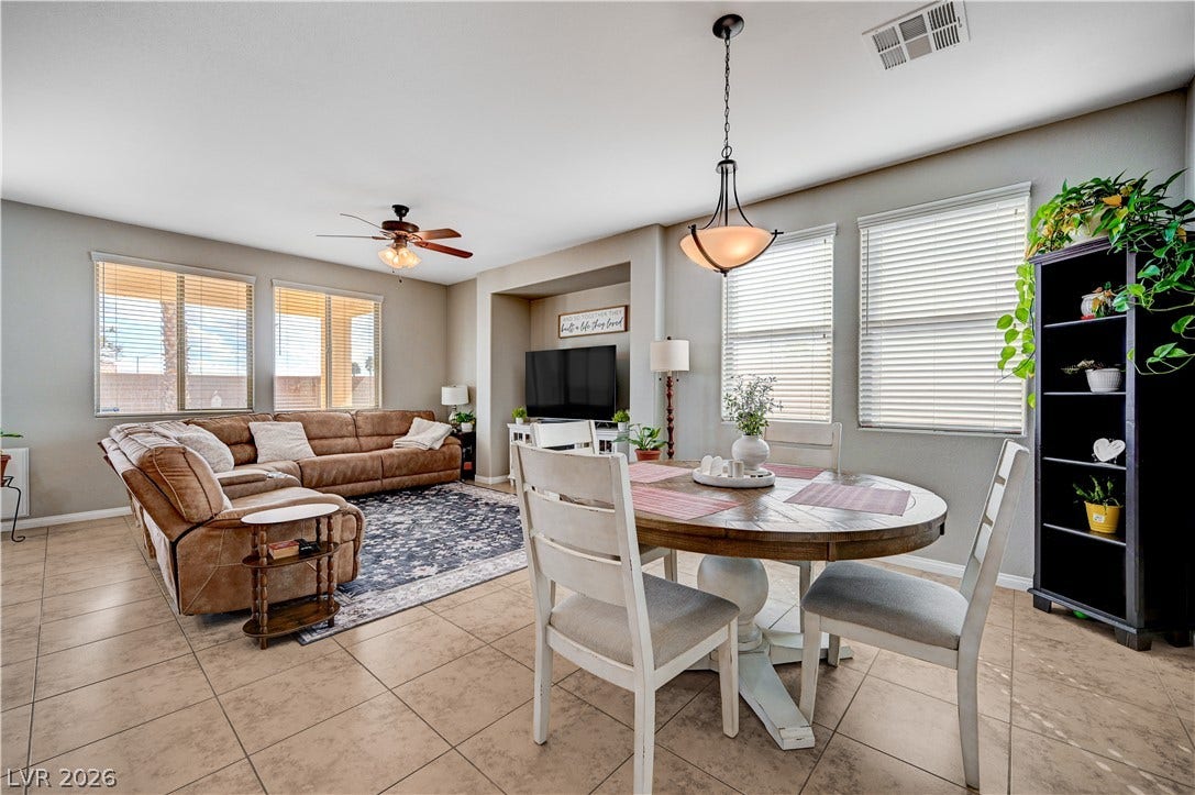 An open living and dining area features tile flooring and natural light from multiple windows.