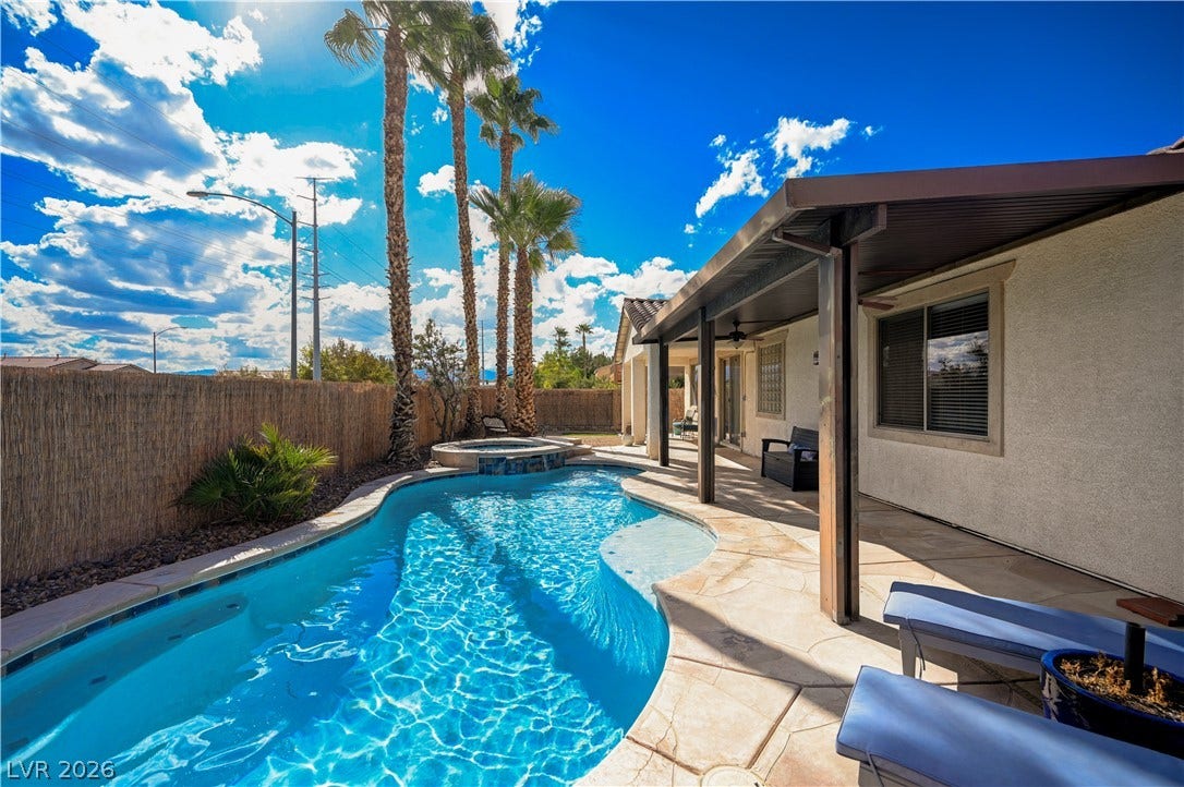 An inviting backyard oasis showcases a sparkling pool flanked by a covered patio structure.