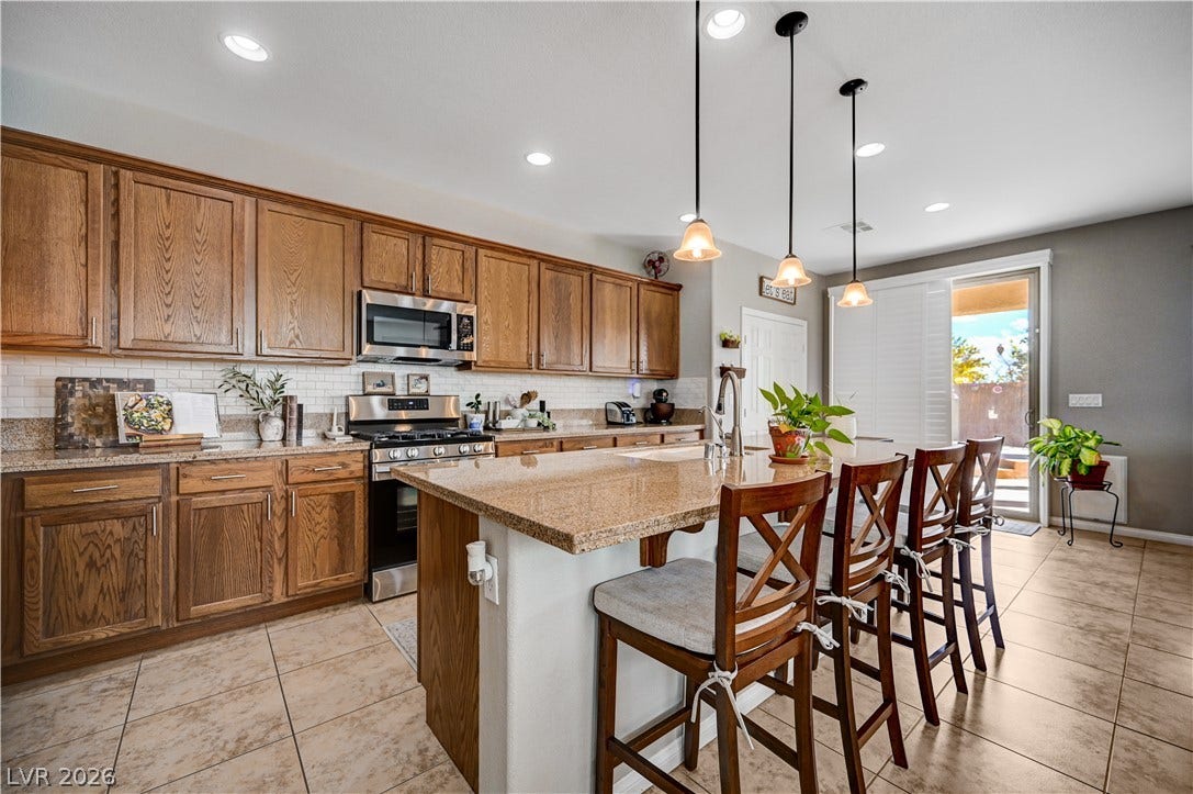 Gleaming tile floors support rich wood cabinets and a granite-topped central island under recessed lighting.