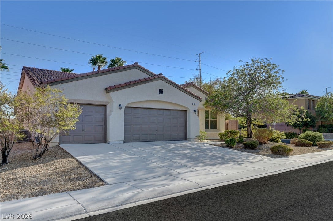 An inviting exterior displays stucco finishes, a Spanish tile roof, and a wide driveway.