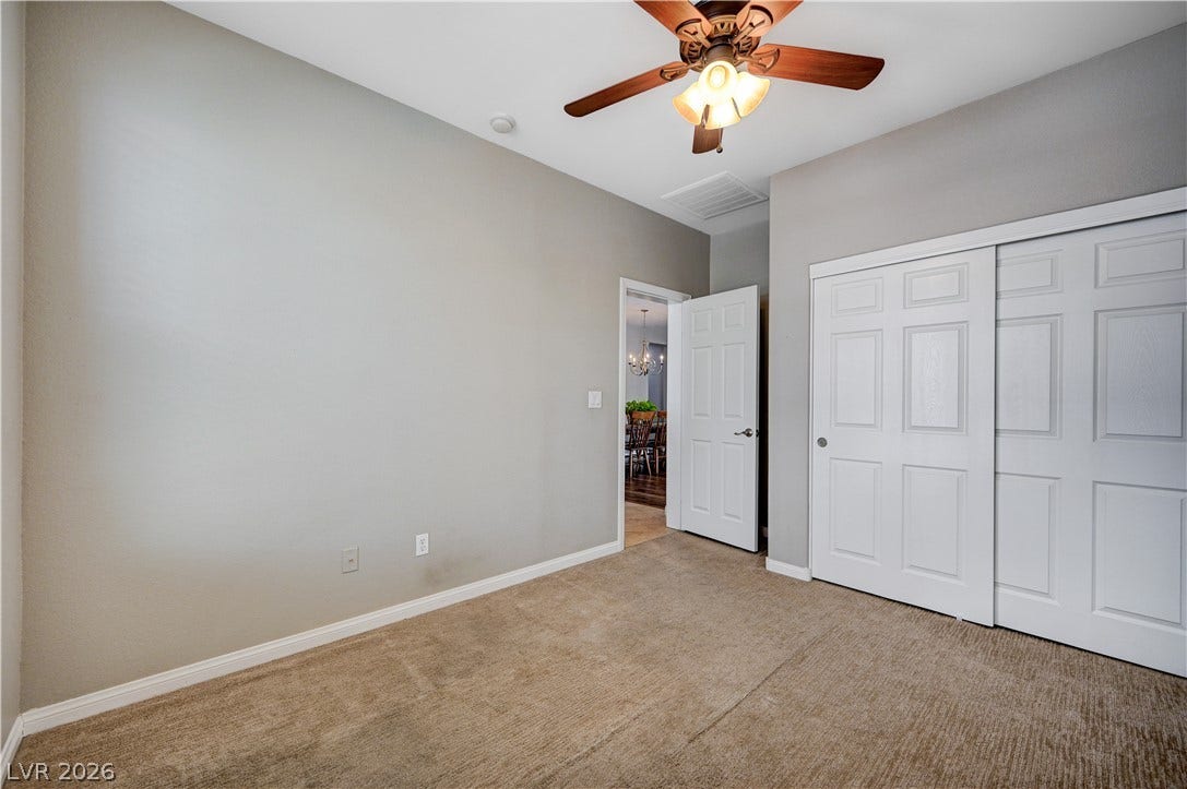 Plush carpeting and tall ceilings define this versatile bedroom space.