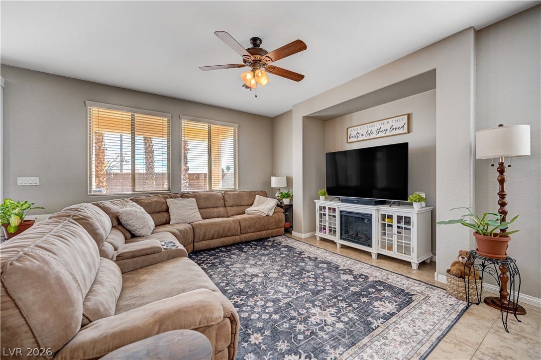 Sunlight streams through large windows into this welcoming living space with tile flooring.