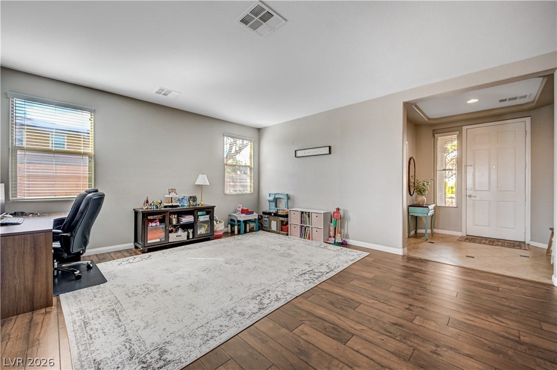 Rich wood-inspired floors flow seamlessly from the welcoming foyer into a versatile living space.