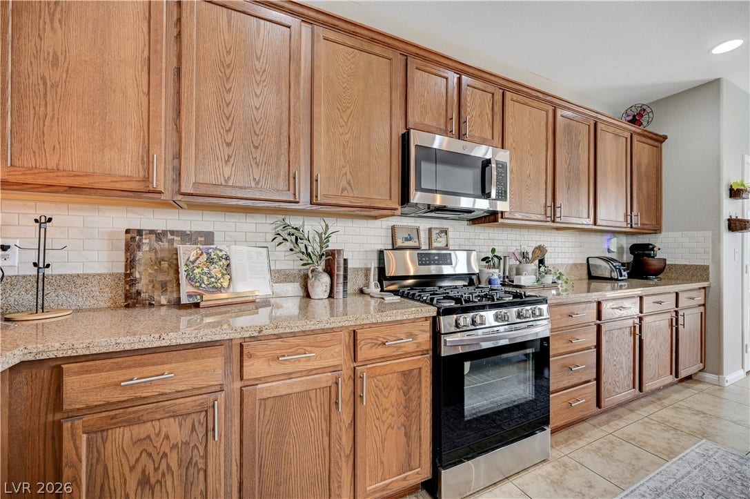 Rich wood cabinetry paired with stone countertops and a classic tiled backsplash defines this kitchen.