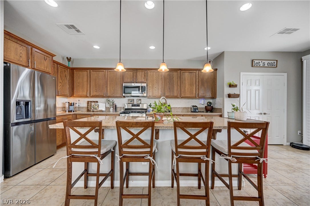 Warm wood cabinetry and stone countertops anchor this central kitchen space.