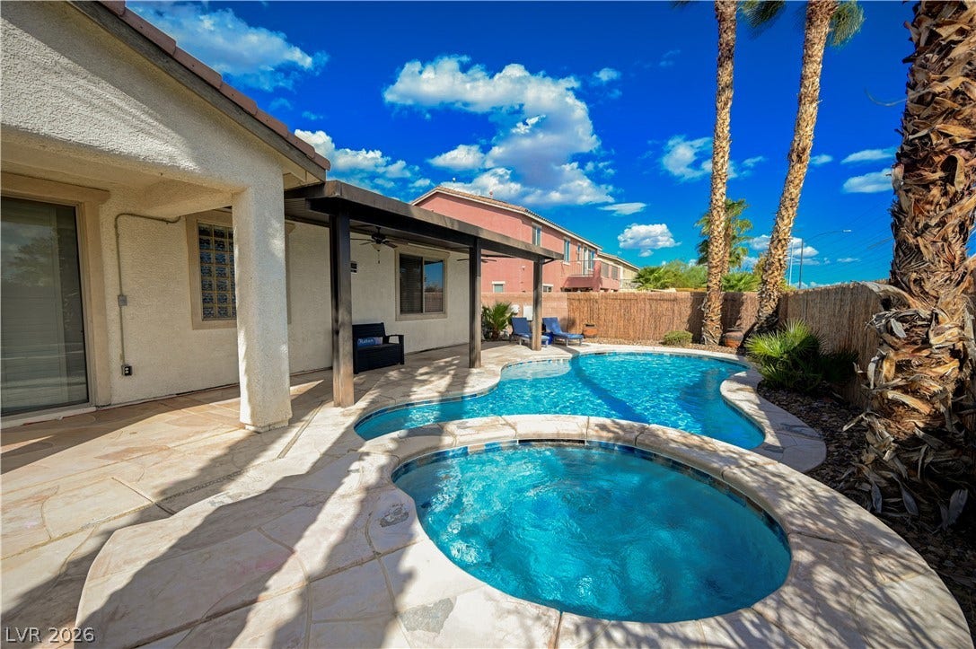 A stone patio wraps around a sparkling swimming pool and elevated circular spa.