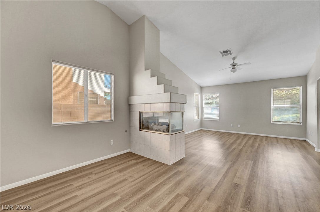 An open floor plan joins the living spaces around a central tiled fireplace.