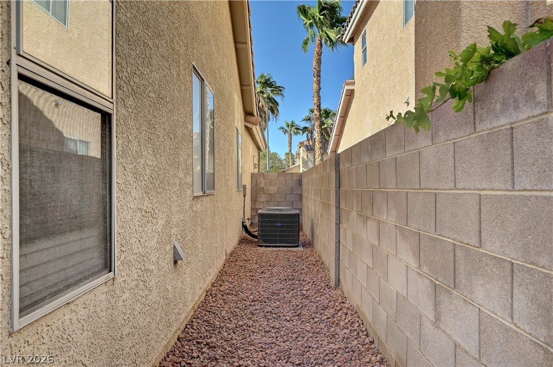 A gravel-lined side yard is enclosed by a privacy wall of concrete blocks.