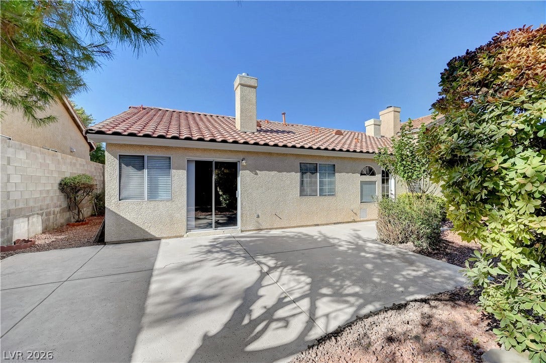 A spacious concrete patio rests beneath a classic Spanish tile roof.