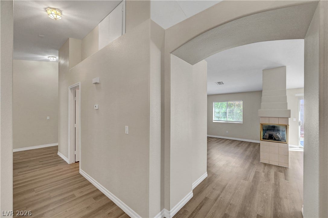 An arched doorway leads into a bright living space featuring a modern tiled fireplace.