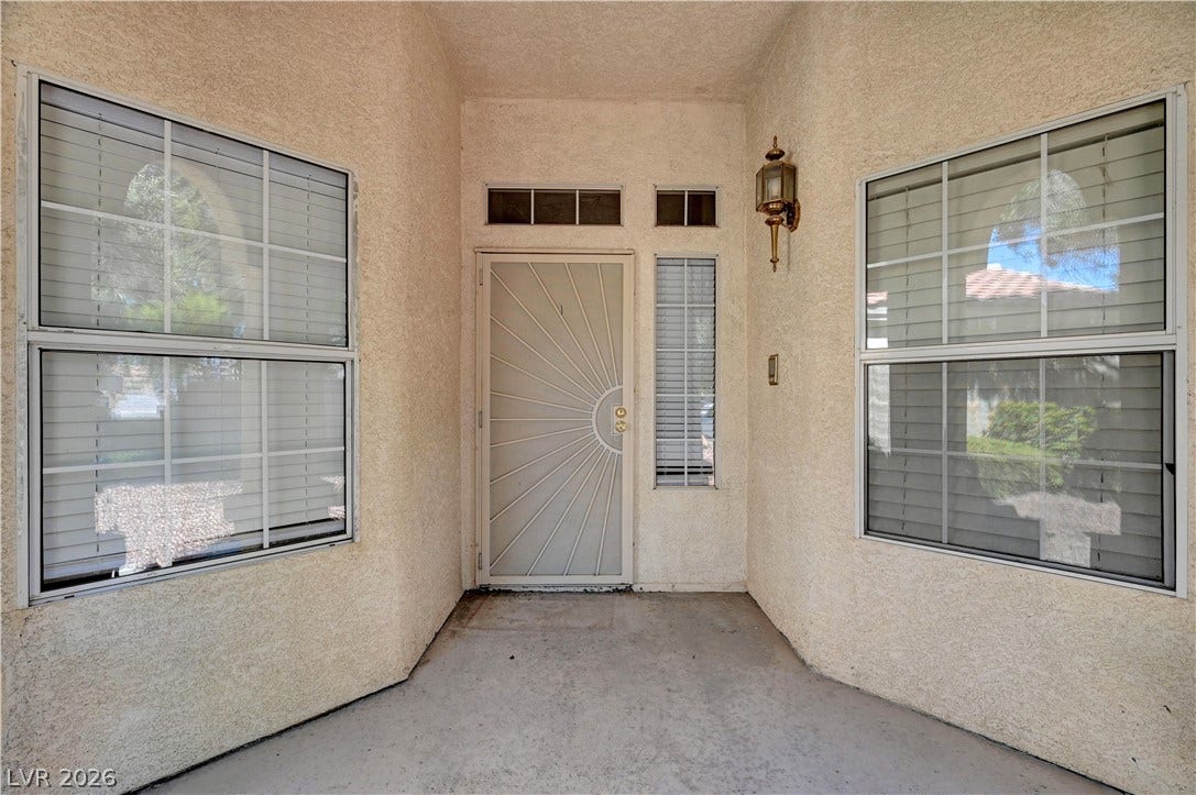 An inviting recessed entry features textured stucco walls and symmetrical windows.