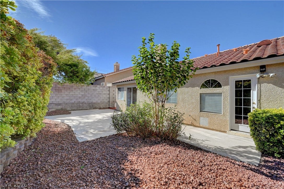 A spacious concrete patio area is bordered by gravel landscaping and a privacy wall.