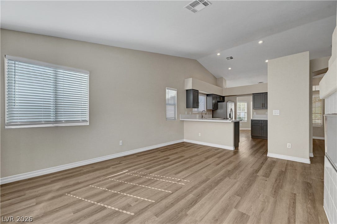 Hardwood floors and vaulted ceilings anchor this open living area connecting seamlessly to the kitchen.