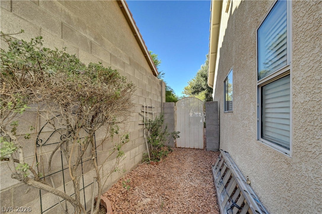 A secure gated side yard features low-maintenance gravel landscaping and high privacy walls.
